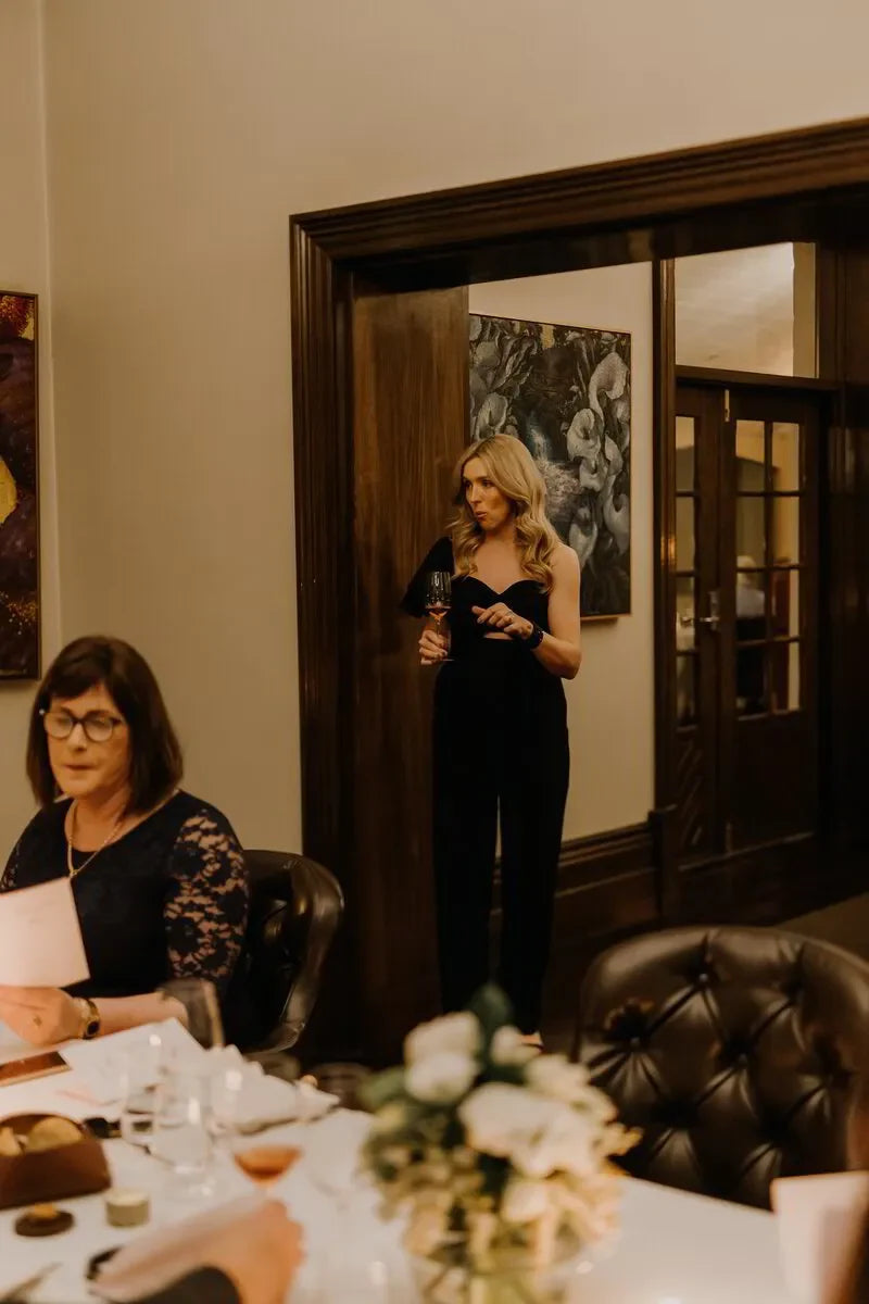 Elegant dinner event in Adelaide with guests, wine glasses, and a floral centerpiece