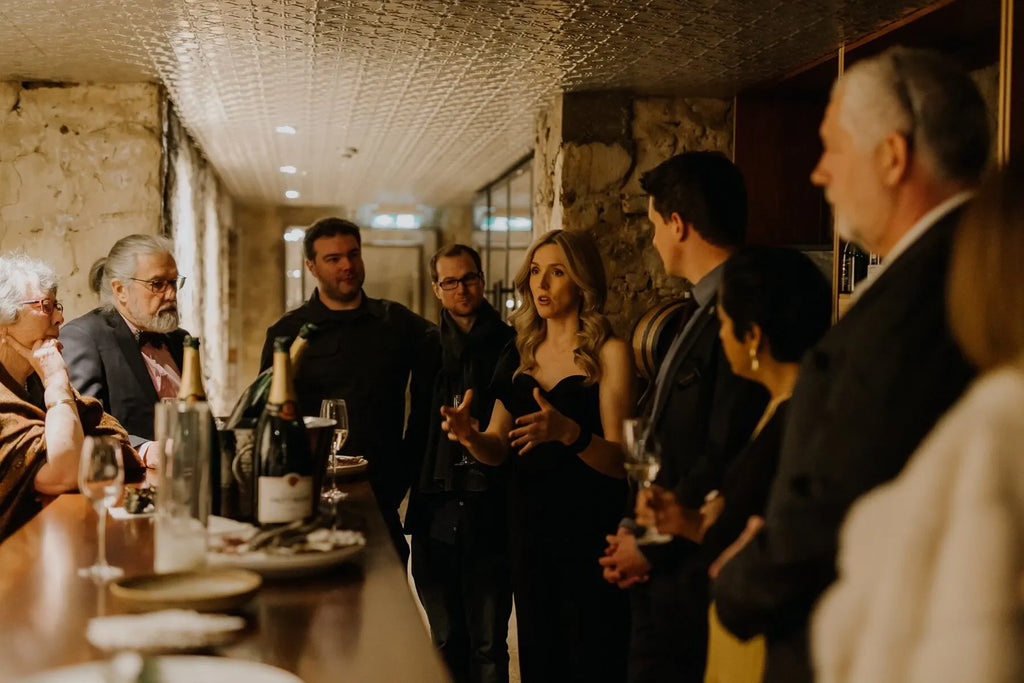 Group at Taittinger dinner in Adelaide cellar with champagne bottles and wine glasses