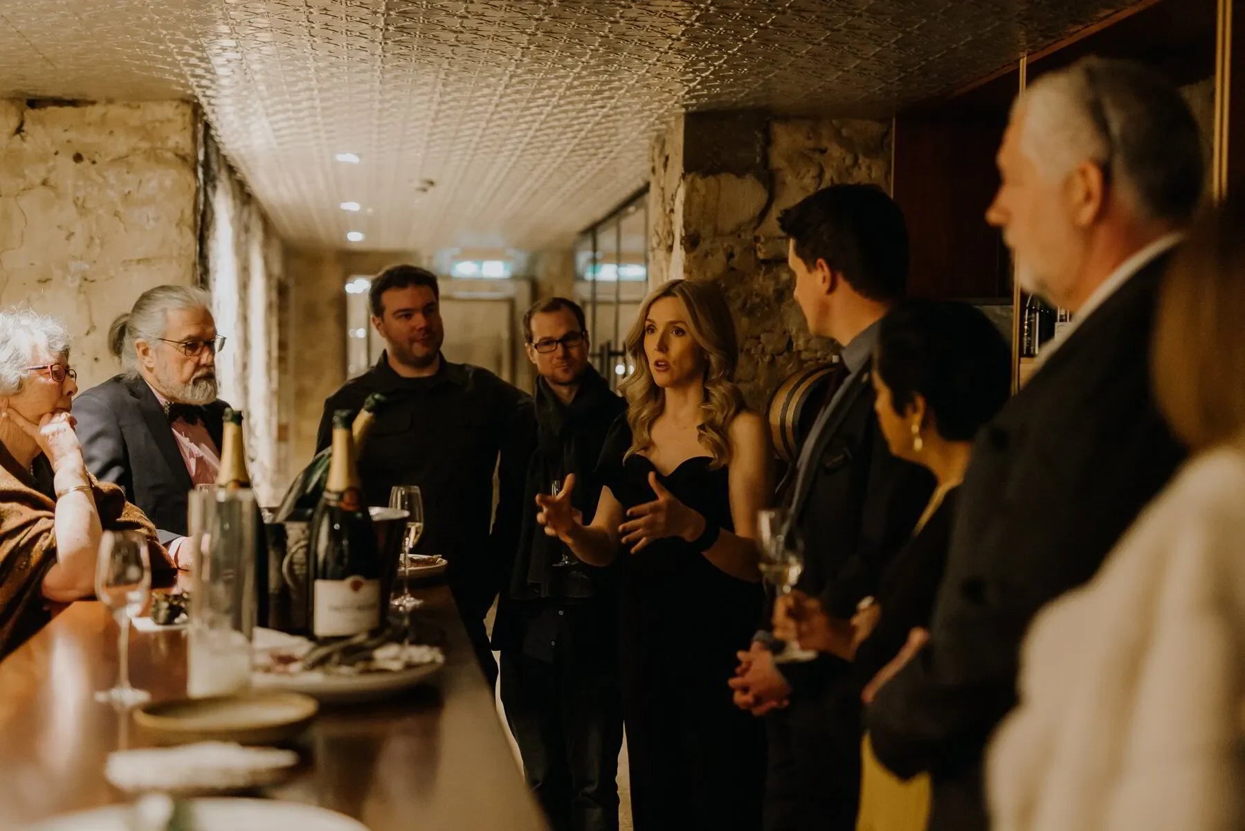 Group at Taittinger dinner in Adelaide cellar with champagne bottles and wine glasses